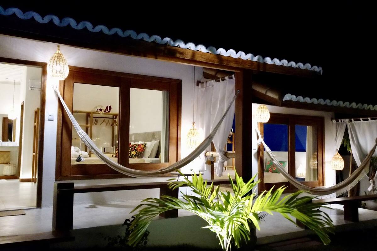 A well-lit room with a large window, a hammock, and a potted plant.