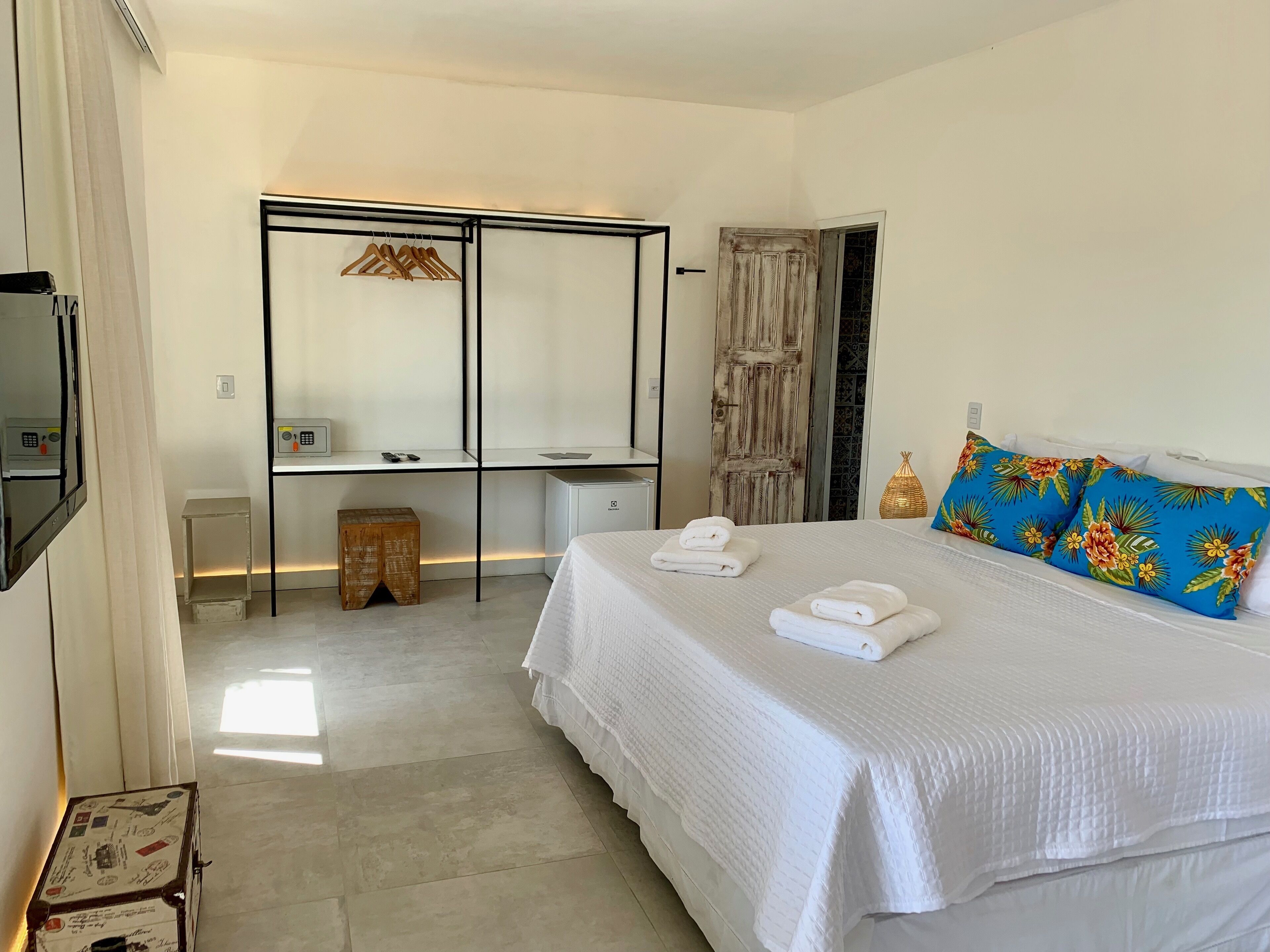 Une chambre d’hôtel avec un grand lit, un bureau avec une chaise, une armoire et une petite table.