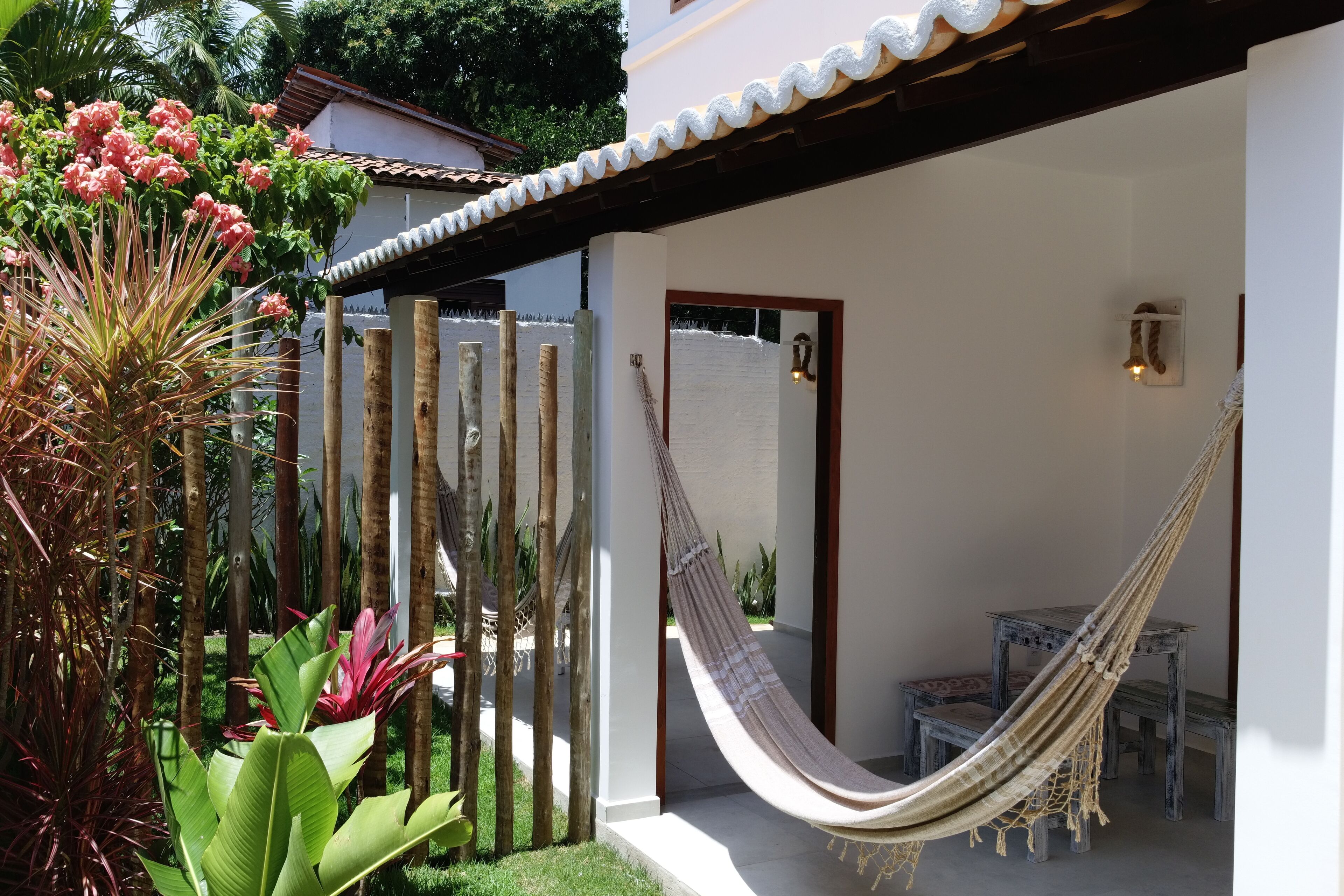 A hammock in a covered outdoor area with a wooden bench and a small table.