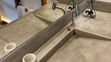 A bathroom with a large mirror, a sink with a modern faucet, and two small, speckled cups on the countertop.