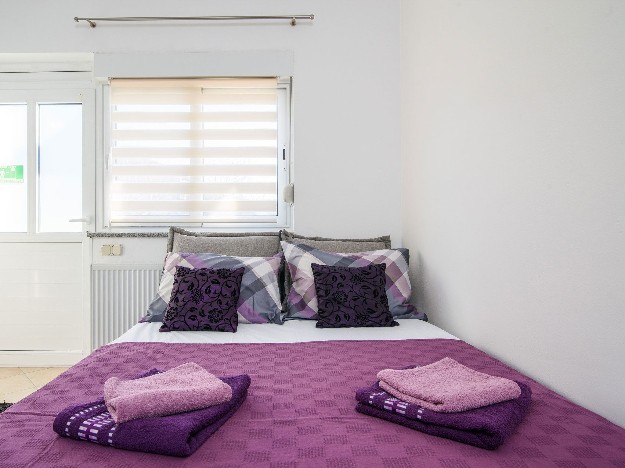 A bedroom with a bed, pillows, and a window with blinds.
