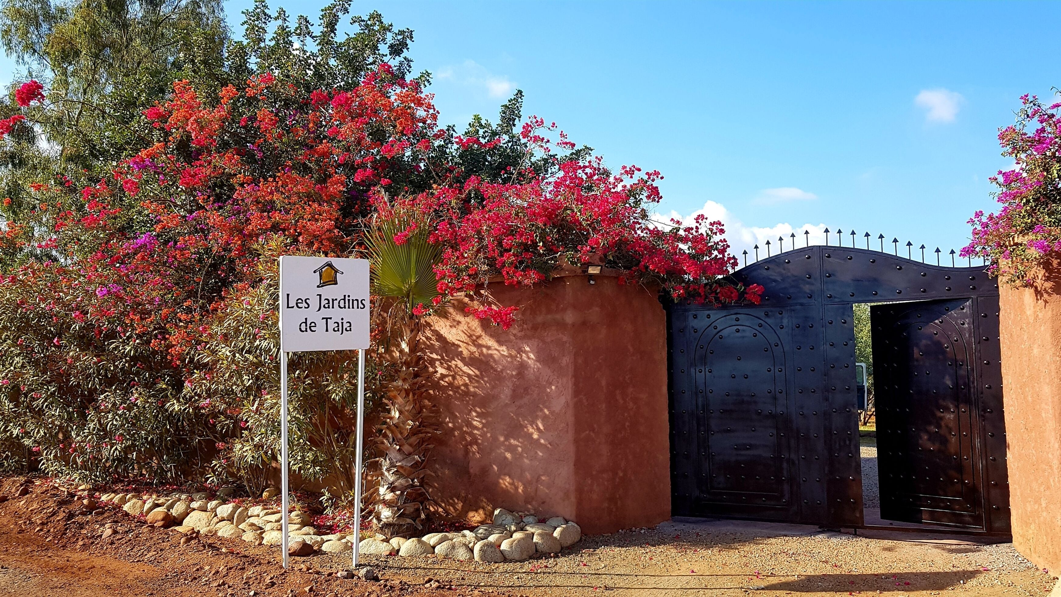 A gated entrance with a sign reading "Les Jardins de Taja".