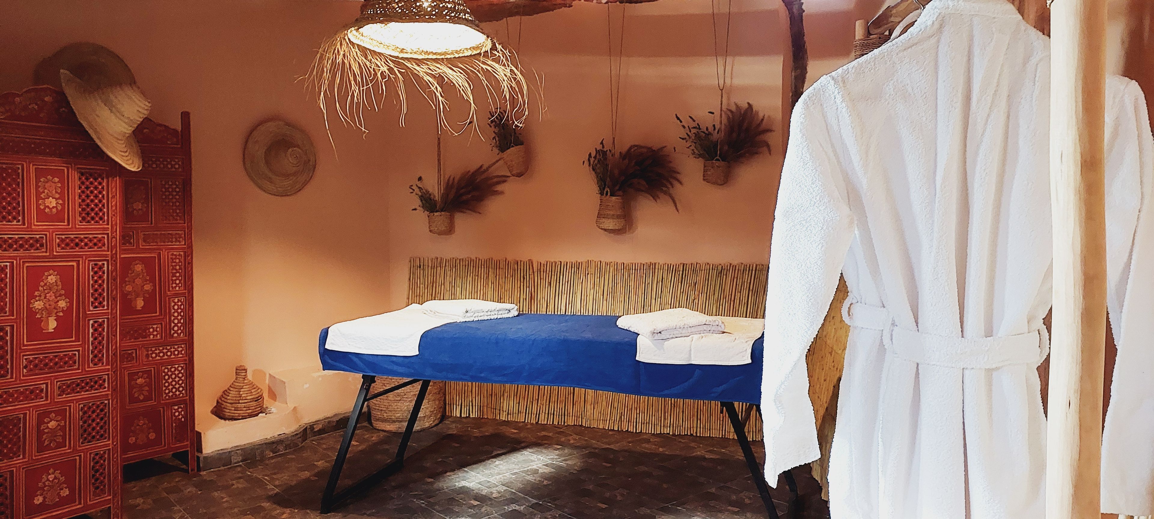 A room with a bed, a red decorative cabinet, and a white robe hanging on the wall.