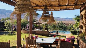Un espace extérieur aménagé avec des meubles en osier, une piscine et une vue sur les montagnes.