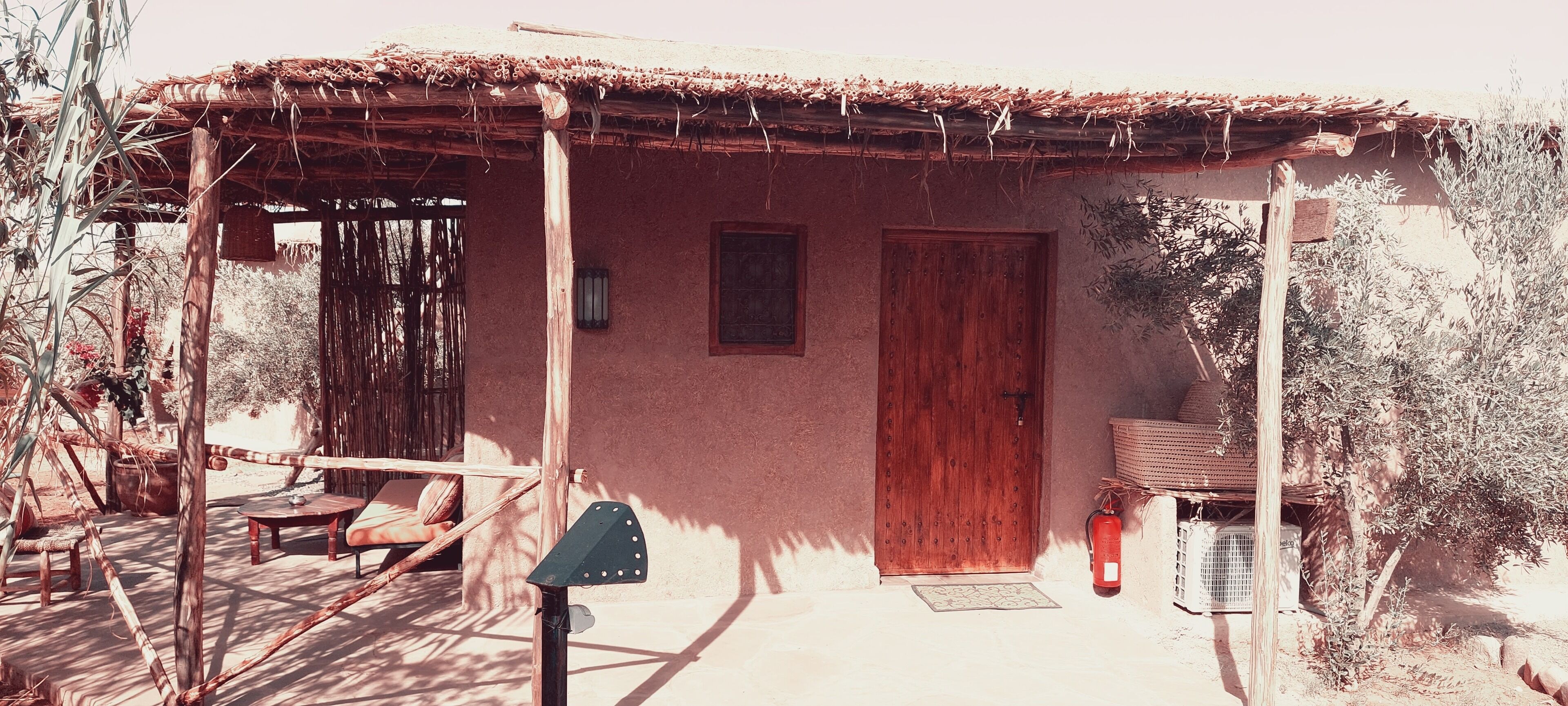 A rustic building with a thatched roof, a wooden door, and a small window.