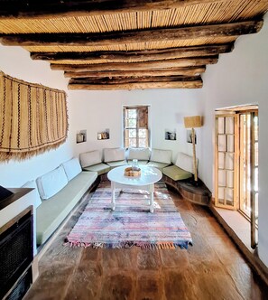 Un salon chaleureux avec un plafond bas, une table basse ronde, un canapé et un tapis à motifs.