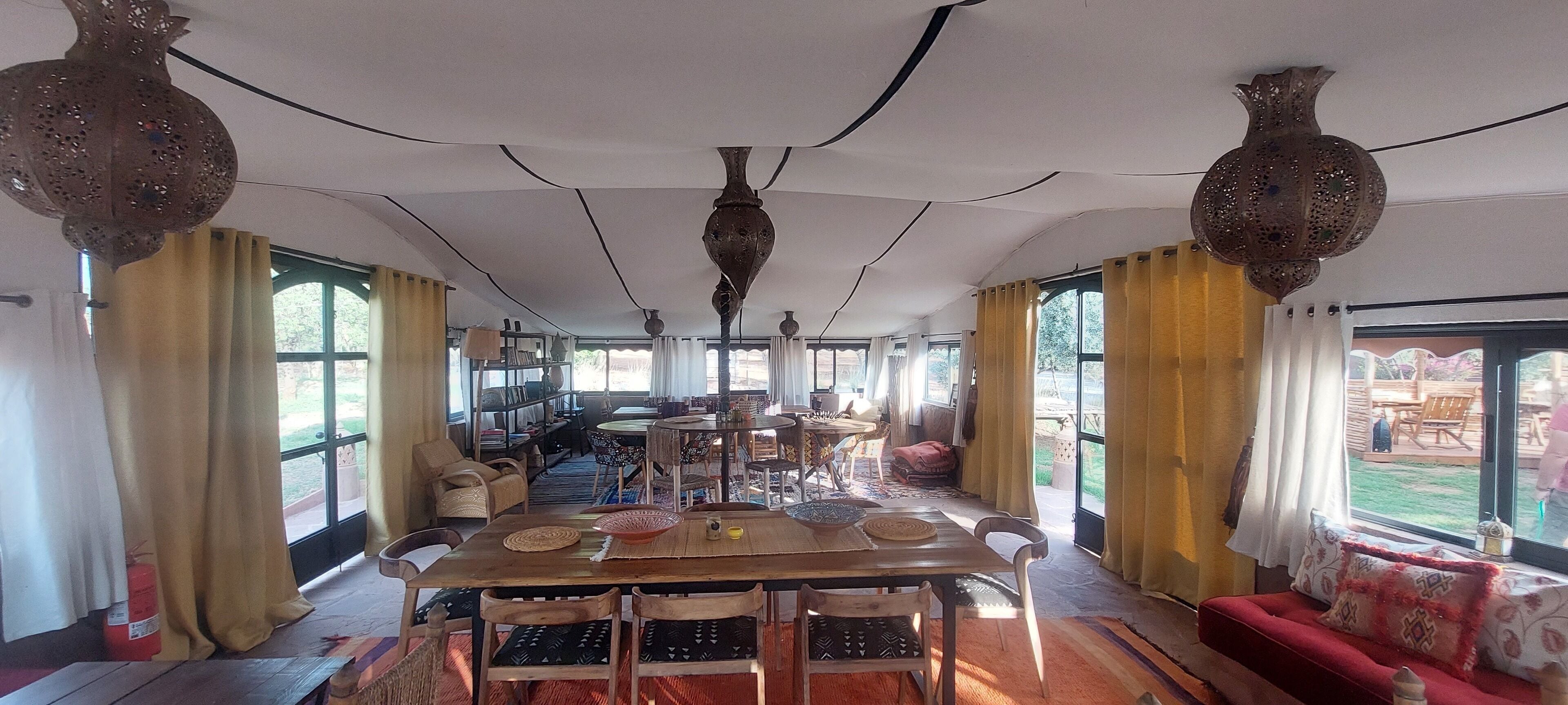 Un comedor espacioso con una mesa larga, sillas y luces decorativas colgantes.