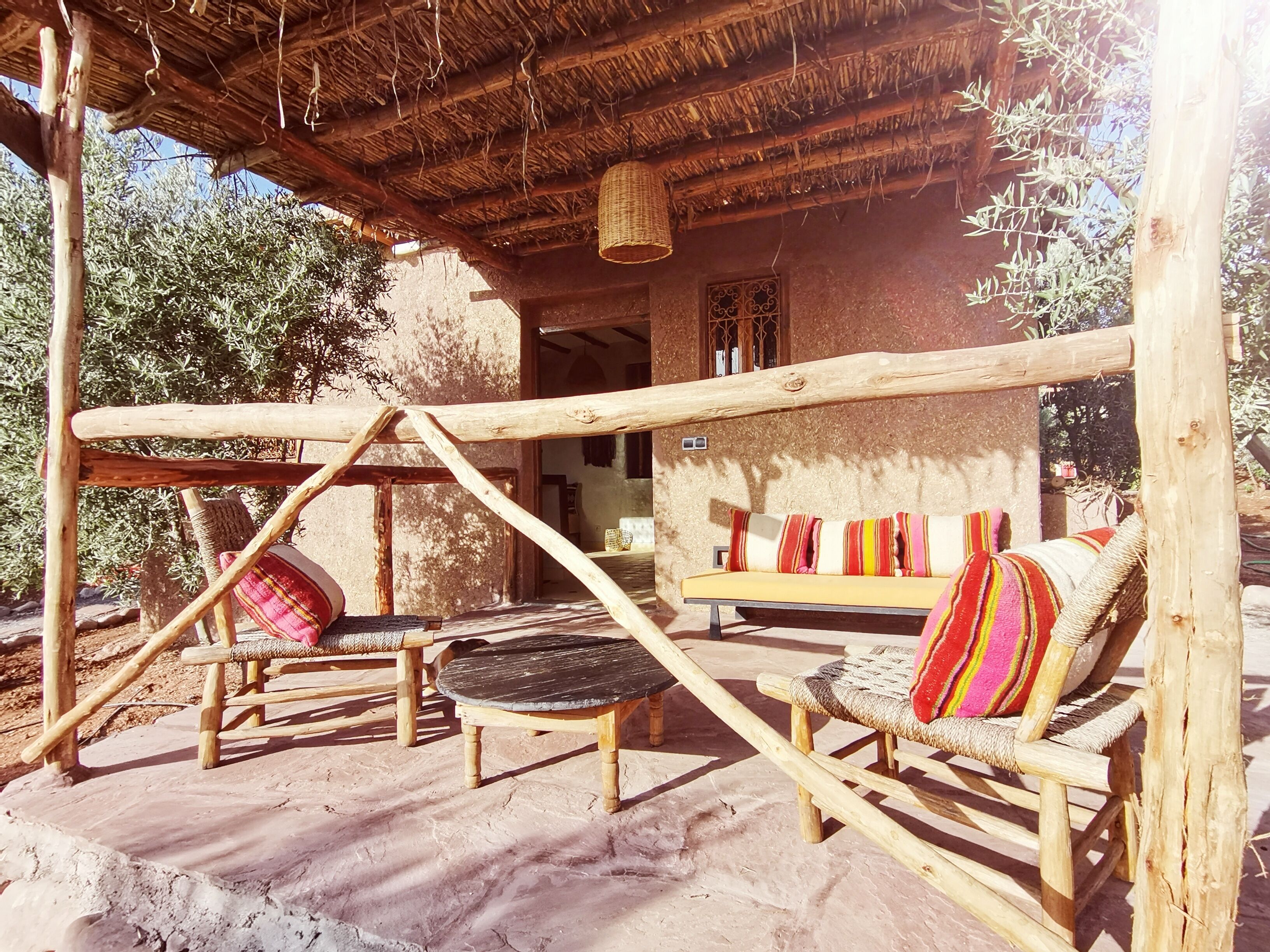 A rustic outdoor seating area with wooden furniture and a thatched roof.
