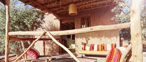 A rustic outdoor seating area with wooden furniture and a thatched roof.