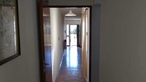 A hallway with a tiled floor leading to a door at the end.