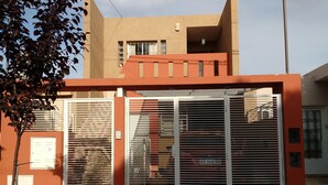 A modern building with a red facade, large metal gates, and a visible car parked inside.