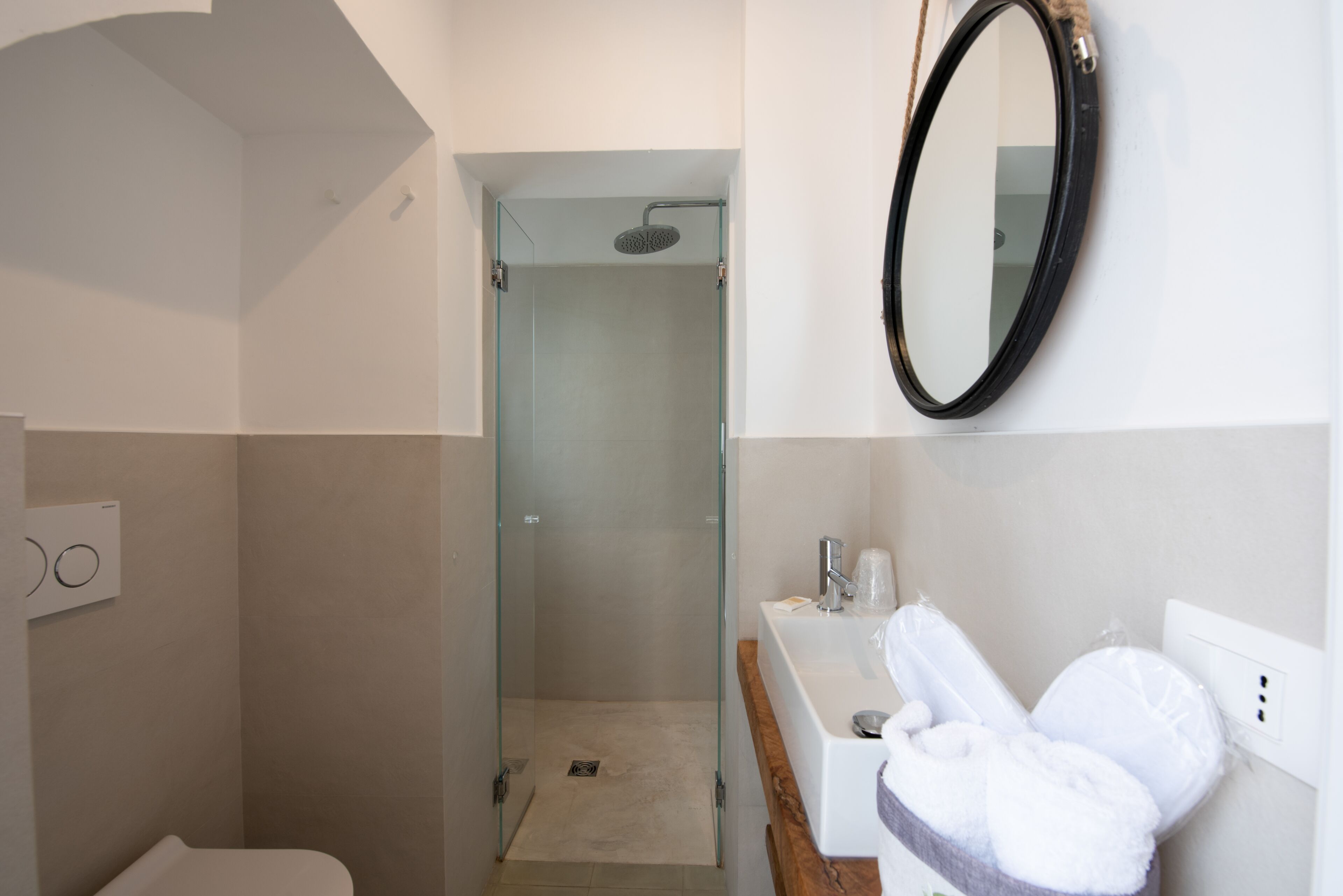 A modern bathroom with a glass-enclosed shower, a white sink, and a mirror on the wall.