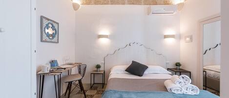 A bedroom with a bed, bedside tables, a desk, and a chair.
