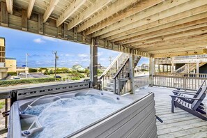 A wooden deck with a hot tub, outdoor seating, and a staircase leading to an upper level. - Casa Blanca | 920 ft from the beach | Private Pool, Hot Tub | Nags Head (Nags Head)