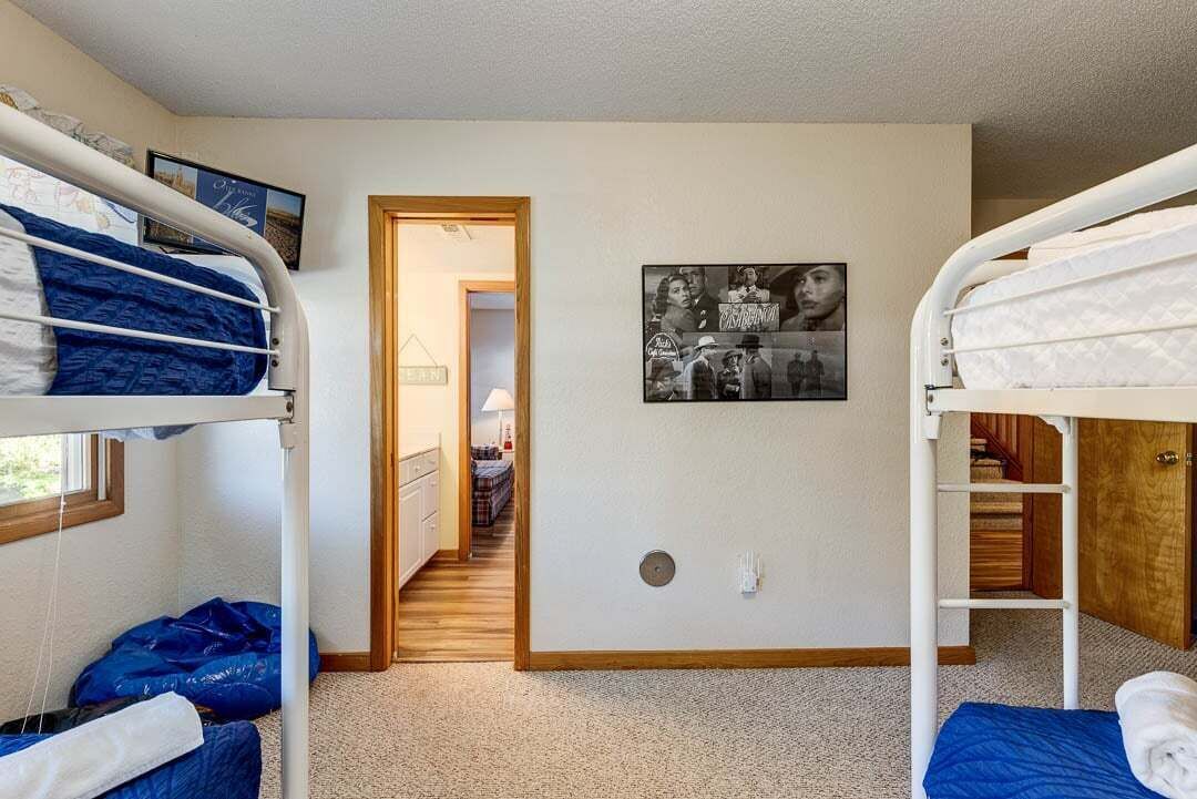 Ein Zimmer mit Etagenbetten, einer Tür zu einem anderen Raum und einem Bild an der Wand.