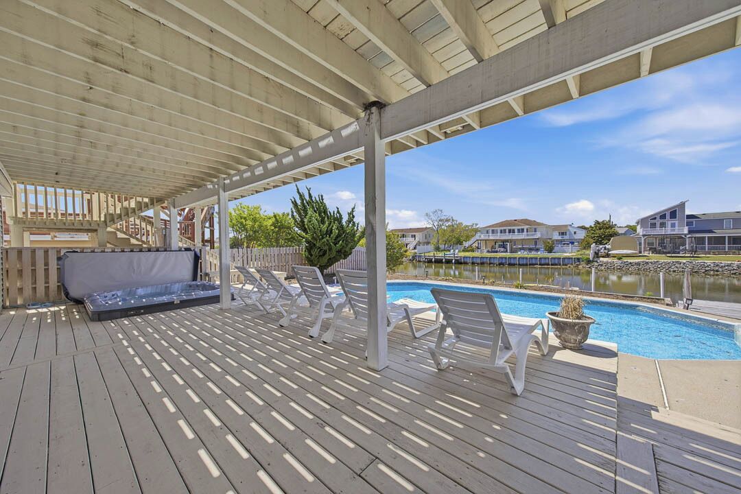Une terrasse couverte avec une piscine, des chaises longues et un canapé.