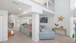 A spacious living area with a high ceiling, a staircase, and a balcony. - Sandpiper Crossing | 555 ft from the beach | Private Pool, Hot Tub (Virginia Beach)