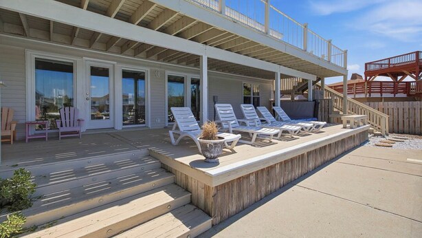 A two-story building with a covered patio area, outdoor seating, and a wooden deck. - Sandpiper Crossing | 555 ft from the beach | Private Pool, Hot Tub (Virginia Beach)