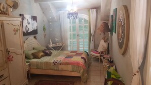 Une chambre à coucher comprenant un lit, une commode, une chaise et une petite table.