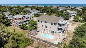 Une grande maison avec une piscine, un patio couvert et une vue sur l’océan.