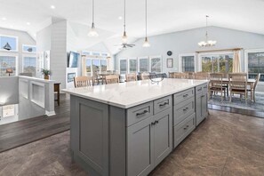 A spacious kitchen with a large island, wooden chairs, and a dining area with a table and chairs.
