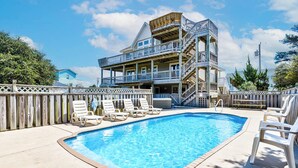 A two-story building with a pool and lounge chairs. - Pelican Pointe | 355 ft from the Beach | Private Pool, Hot Tub | Corolla (Corolla)