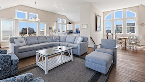 A spacious living room with a sectional sofa, a coffee table, and patterned chairs. - Pelican Pointe | 355 ft from the Beach | Private Pool, Hot Tub | Corolla (Corolla)
