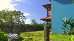 A lush garden with a pathway leading to a building with a blue exterior and a tiled roof.