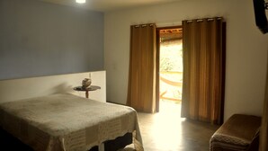 A bedroom with a bed, a small table, a bench, and a ceiling fan.