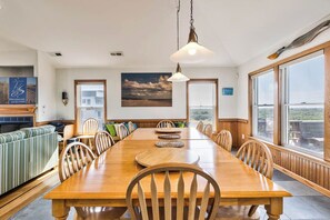 Enjoy meals in this dining area with a long table, green-striped sofa, and a view of the outdoors.