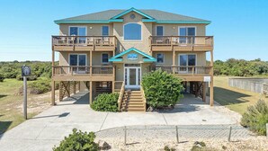 A two-story building with a balcony on each floor, a central entrance, and a small porch area. - Sea Song II | 470 ft from the Beach | Private Pool, Hot Tub | Nags Head (Nags Head)