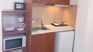 Una cocina compacta equipada con microondas, cafetera y un refrigerador pequeño.