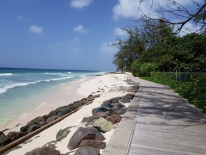 A beach with a concrete walkway, rocky shoreline, and palm trees. - 2 minute Walk to Beach, Newly Renovated, 2 Bed 2 Bath Apartment #1
Shenstone (Rockley)