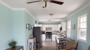 A spacious living room with a wooden coffee table, a dining area with a wooden table and chairs, a kitchen with white cabinets and a stove, and a ceiling fan. - 2 minute Walk to Beach, Newly Renovated, 2 Bed 2 Bath Apartment #1
Shenstone (Rockley)