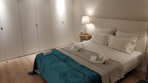 A bedroom with a bed, a nightstand, a lamp, and a wardrobe.