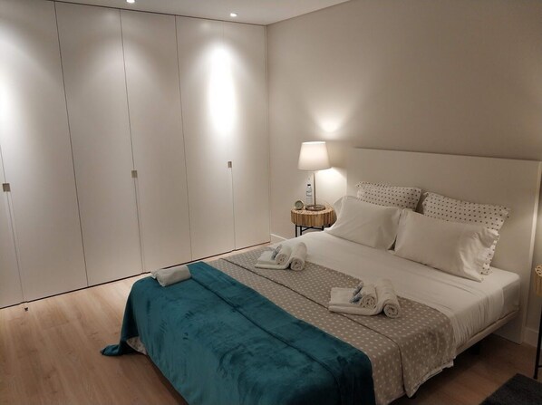 A bedroom with a bed, a nightstand, a lamp, and a wardrobe.