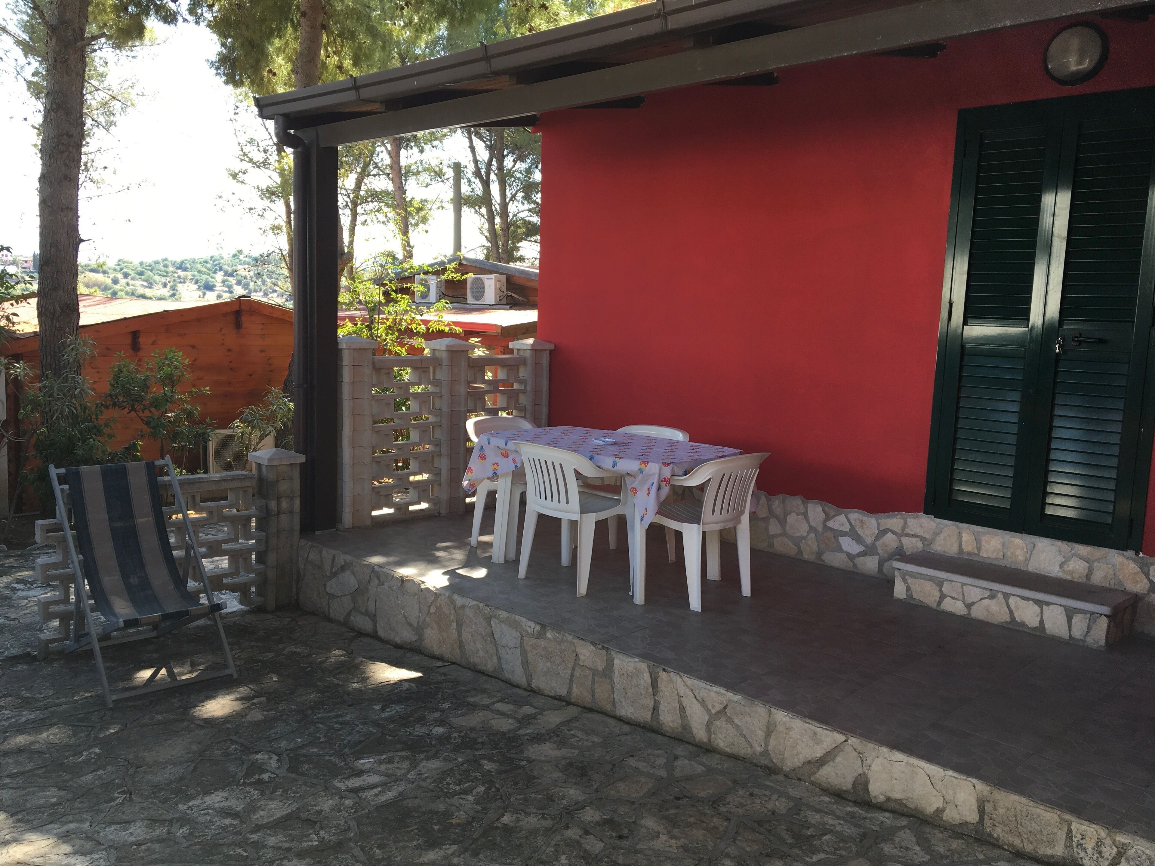 A red building with a covered patio area featuring a table and chairs.