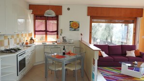 A compact kitchen with a dining area, a sofa, and a colorful rug. - Apartment in Malcesine on Lake Garda. New, with panoramic Parking. (Malcesine)