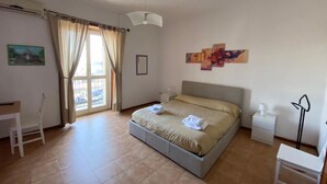 A bedroom with a bed, a desk, a chair, a nightstand, and a lamp. - Street Art House (Catania)