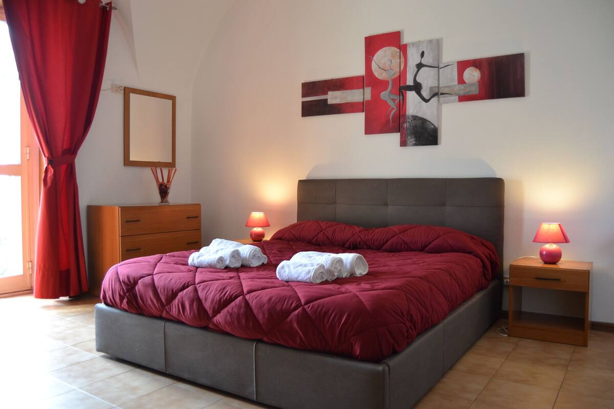 Une chambre à coucher avec un grand lit, deux tables de chevet avec des lampes, une commode et un tableau au mur.