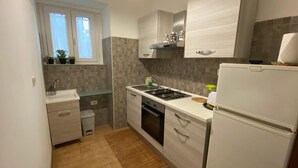 A compact kitchen with a built-in oven, a sink, and a refrigerator. - Street Art House (Catania)