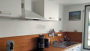 A modern kitchen with white cabinets, a wooden countertop, a built-in dishwasher, and a coffee maker. - House / Villa - Agon Coutainville (Agon-Coutainville)