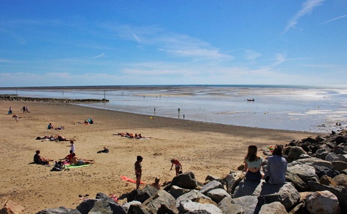 Ein Strand mit entspannten Personen und spielenden Kindern.