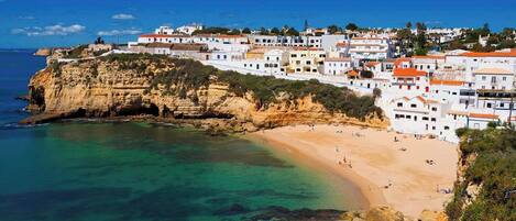 Un pueblo costero con edificios blancos, una playa y acantilados.