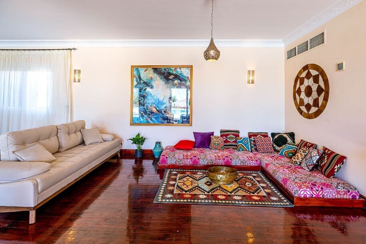 A living room with a sofa, a patterned rug, and a large abstract painting on the wall.