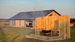 A modern house with a large garage and a wooden outdoor kitchen area. - Stunning luxury cliff top retreat - direct access to the South West Coast Path. (Bude)