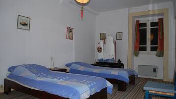Habitación de hotel con dos camas, una mesita de noche, una silla y una ventana con cortinas.