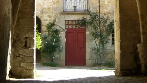 An arched stone corridor with a red door and a window with a balcony. - Landmarked stone house by a stream with extraordinary charm (Frontenay)
