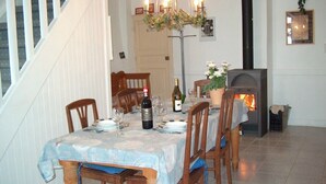A dining room with a table set for four, a fireplace, and a staircase. - Landmarked stone house by a stream with extraordinary charm (Frontenay)