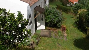 A white building with a red-tiled roof, a garden with various plants, and a view of the sea. - Country Cottage - Cedros, typical Azorien Big House with garden and seaview (Cedros)